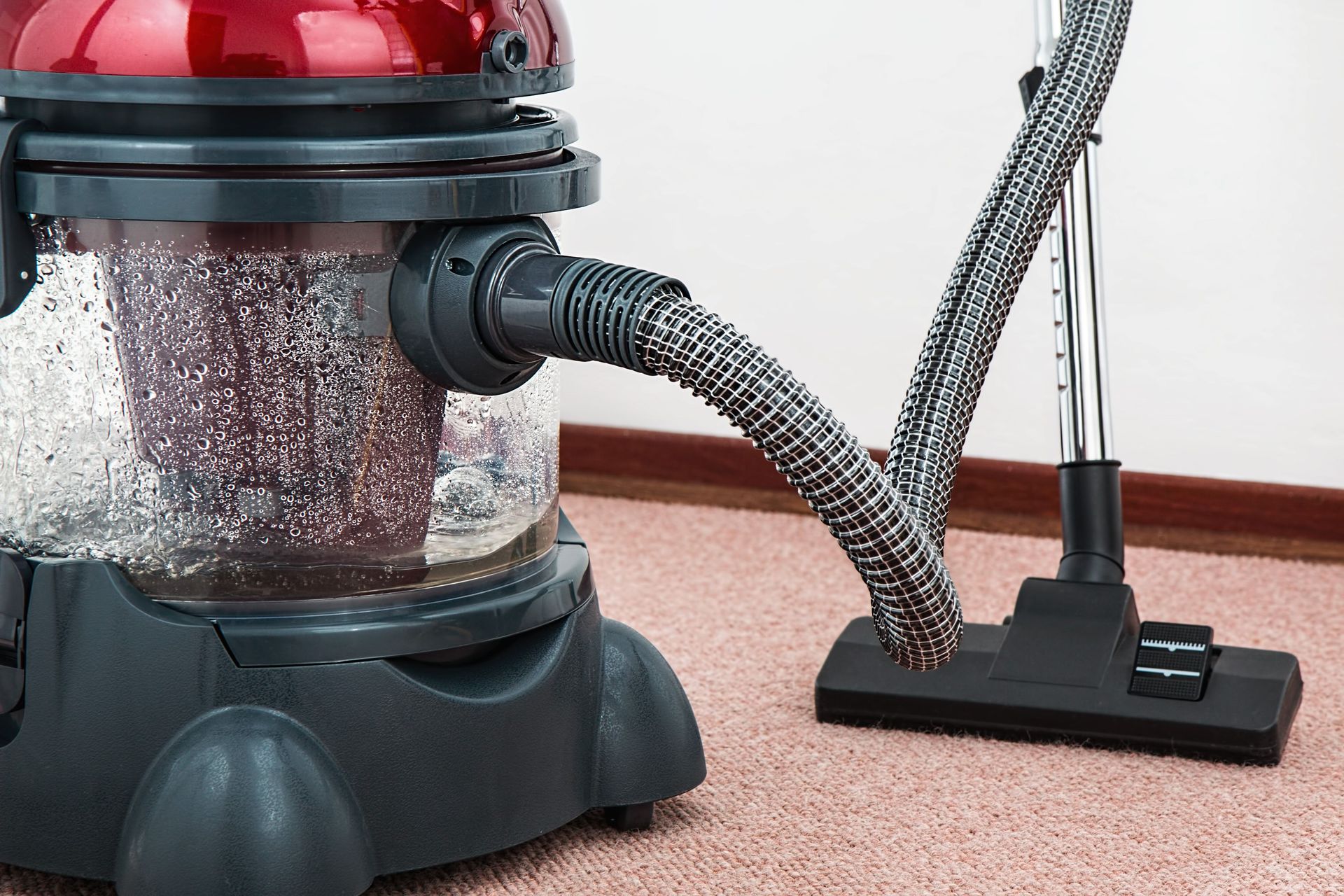 Close-up of a modern vacuum cleaner with water filtration on carpet floor indoors.